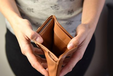 Une femme d'âge moyen ouvre un porte-monnaie sans argent à l'intérieur
